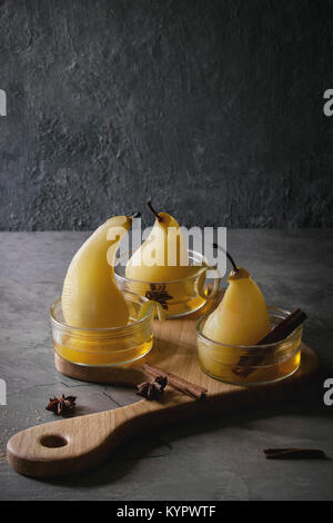 Traditionelle Dessert pochierte Birnen in Weißwein im Glas serviert Schüsseln mit Sirup und Zitronenschale auf Holz das Brett über grau Textur Tabelle. Stockfoto