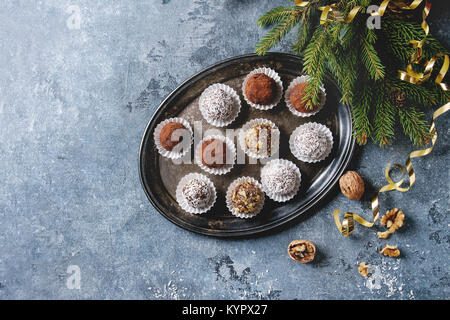 Auswahl an hausgemachten dunkle Schokolade Trüffel mit Kakao, Kokosnuss, Walnüsse als Weihnachtsgeschenk auf vintage Fach mit Tannenbaum, Weihnachtsschmuck Stockfoto