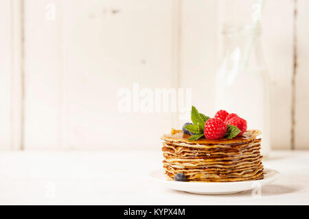 Milch und Stapel Pfannkuchen mit Beeren und Honig Stockfoto