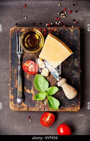 Frische Zutaten für die italienische Küche (Parmigiano, Tomaten, Basilikum, Olivenöl) auf rustikalen Hintergrund. Ansicht von oben Stockfoto