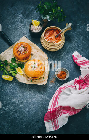 Würzige Pav Bhaji Masala gefüllt zwischen der Gebutterte Schieberegler Brötchen, gekrönt mit gehackten Zwiebeln und Koriander. Stockfoto