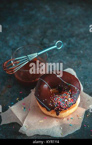 Schokolade Donut mit Wachspapier und Getränk auf Holztisch Schokolade Donut mit Wachspapier und Getränk auf Holztisch