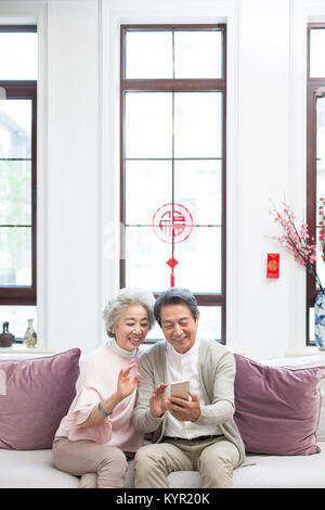 Gerne älteres Paar video chat auf Smart Phone während des chinesischen neuen Jahres Stockfoto