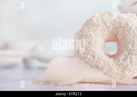 Nahaufnahme eines weißen Donut mit Kokosnuss Topping auf einem hellen Hintergrund. High key Essen Fotografie. Stockfoto