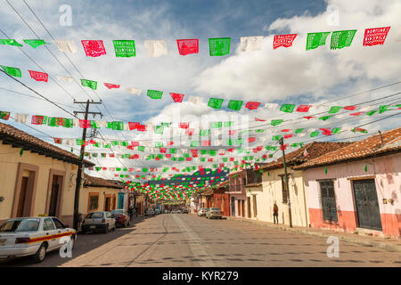 SAN CRISTOBAL, MEXIKO - 27. NOVEMBER: Nicht identifizierte Personen in einer ruhigen Straße mit bunten Papierfahnen oder Papel picado in der Mexikanischen Flagge Farben gefüttert Stockfoto