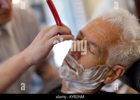 Ein alter Mann mit einer geraden Kante razor bei einem Friseur rasieren. Nahaufnahme Stockfoto
