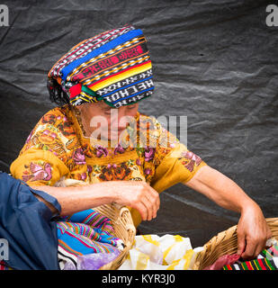 SAN JUAN OSTUNCALCO, GUATEMALA - 24. Juni: Nicht identifizierte Maya Frau in traditioneller Kleidung, Waren zu verkaufen, in geflochtenen Körben am San Juan Ostuncalco fair Stockfoto