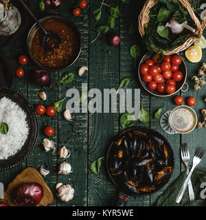 Blick von oben auf die gekochten Muscheln mit Schalen in Pfanne mit Tomaten, Kräuter und Wein am Tisch serviert Stockfoto