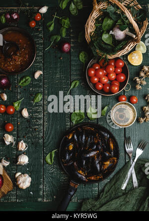 Blick von oben auf die gekochten Muscheln mit Schalen in Pfanne mit Tomaten, Kräuter und Wein am Tisch serviert Stockfoto