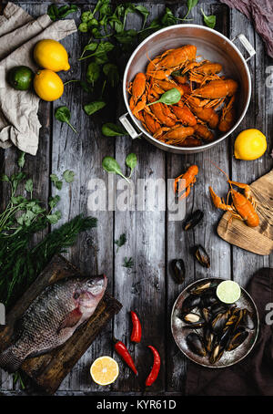 Blick von oben auf die verschiedenen köstlichen Fisch mit Zitronen und Kräutern auf rustikalen Holztisch Stockfoto