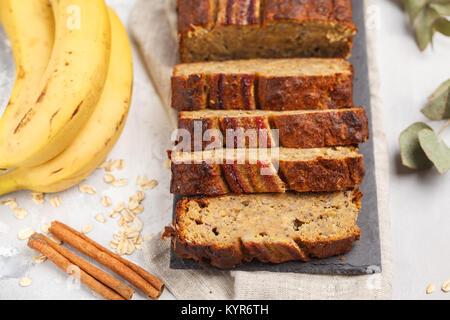 In Scheiben geschnitten vegan Bananenbrot mit Zimt auf schwarzem Schiefer. Grauer Hintergrund. Veganes Essen Konzept. Stockfoto