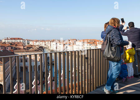 Touristen betrachten den Canale Grande und die Dächer von Venedig aus Fondaco dei Tedeschi Dachterrasse mit einer jungen Familie Fotografieren auf Handys Stockfoto