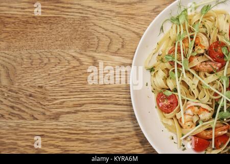 Halbjahr eine weiße Schale mit Garnelen Garnelen und Linguini auf einem Holz Tisch von oben gesehen Stockfoto