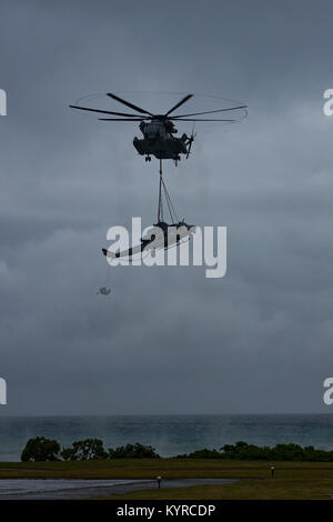 Ein US-Marine CH-53E Super Stallion "Helikopter mit 1. Marine Flugzeugflügel, und 3. Marine Logistics Group, Hubschrauber Support Team offload eine UG-1 Y "Venom" Huey Hubschrauber nach einer Notlandung am Strand, Uruma Naval Base White Beach, Okinawa, Japan. 8. Januar 2018. Die UH-1Y Ikeijina Hubschrauber landete auf einer kleinen Insel vor der Insel Okinawa, nach Anzeichen dafür, dass der Rotor mit gefährlich hohen Geschwindigkeiten bewegte. Niemand wurde bei dem Vorfall verletzt. (U.S. Marine Stockfoto