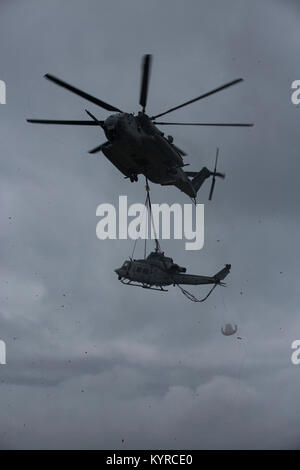 Ein US-Marine CH-53E Super Stallion "Helikopter mit 1. Marine Flugzeugflügel, und 3. Marine Logistics Group, Hubschrauber Support Team offload eine UG-1 Y "Venom" Huey Hubschrauber nach einer Notlandung am Strand, Uruma Naval Base White Beach, Okinawa, Japan. 8. Januar 2018. Die UH-1Y Ikeijina Hubschrauber landete auf einer kleinen Insel vor der Insel Okinawa, nach Anzeichen dafür, dass der Rotor mit gefährlich hohen Geschwindigkeiten bewegte. Niemand wurde bei dem Vorfall verletzt. (U.S. Marine Stockfoto