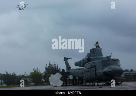 Ein US-Marine CH-53E Super Stallion "Helikopter mit 1. Marine Flugzeugflügel, und 3. Marine Logistics Group, Hubschrauber Support Team offload eine UG-1 Y "Venom" Huey Hubschrauber nach einer Notlandung am Strand, Uruma Naval Base White Beach, Okinawa, Japan. 8. Januar 2018. Die UH-1Y Ikeijina Hubschrauber landete auf einer kleinen Insel vor der Insel Okinawa, nach Anzeichen dafür, dass der Rotor mit gefährlich hohen Geschwindigkeiten bewegte. Niemand wurde bei dem Vorfall verletzt. (U.S. Marine Stockfoto