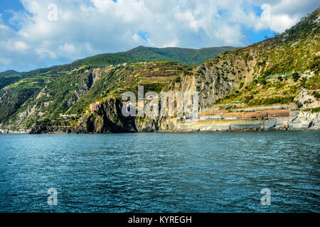 Die schroffen und steilen Küste in der Nähe von Riomaggiore Italien, Teil der Cinque Terre, mit einem Hang Village und ein Zug entlang dem Bergabhang läuft Stockfoto