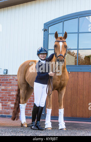 Deutsches Reitpony. Junge Reiter neben Fuchswallach. Großbritannien Stockfoto