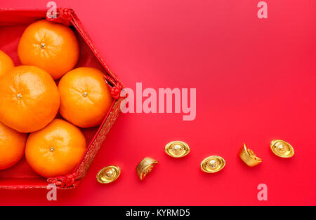 Gruppe von orange Tangerine in der chinesischen Muster Fach mit gold Barren auf dem roten Tisch. Chinesisches neues Jahr anhand von quantitativen Simulatio. Chinesische Sprache ingot ist wohlhabend Stockfoto