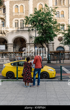 Budapest, Ungarn - 13. August 2017: Touristen lesen von Landkarten in der Nähe von Yellow cab in der Andrassy Straße in Budapest Stockfoto