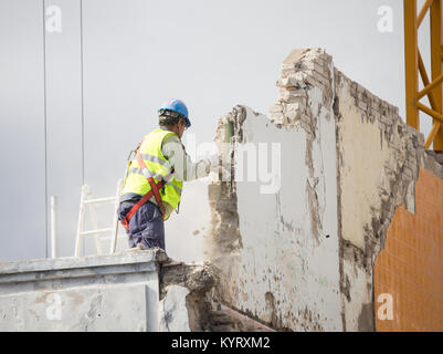 Handwerker demolieren Wand auf hohe Gebäude ohne Sicherheit am Kabelbaum angeschlossen werden. Stockfoto