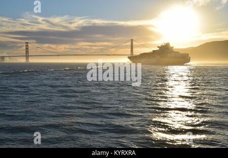 Containerschiff NYK Konstellation verläßt die Bucht von San Francisco unter der Golden Gate Bridge in den Sonnenuntergang. Stockfoto