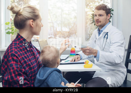 Kinderarzt gibt ein Rezept, um die Mutter nach der Konsultation Stockfoto