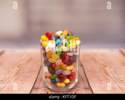 Bunte Jelly Beans in einem Glas auf einem hölzernen Hintergrund Stockfoto