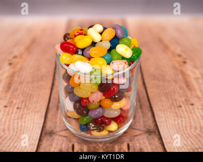 Bunte Jelly Beans in einem Glas auf einem hölzernen Hintergrund Stockfoto