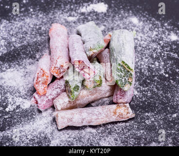 Turkish Delight Stücken Puderzucker auf eine schwarze Fläche Stockfoto