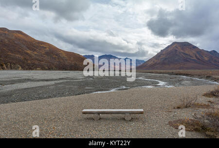 Eine Holzbank sitzt leer mit Blick auf eine geflochtene Fluss im Denali Nationalpark. Stockfoto