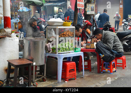 Hanoi, Vietnam - 13. Dezember 2017. Kunden essen an einer Garküche in der historischen Altstadt von Hanoi Stockfoto