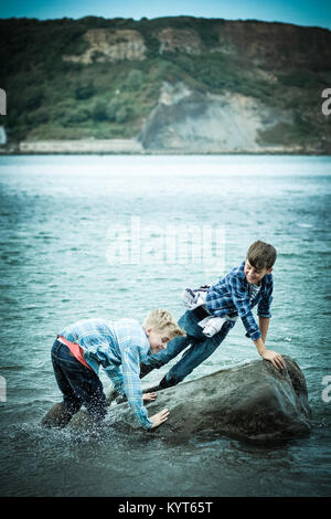 Zwei Brüder, Jungen 12 und 10 Jahre, im Meer, Krabben, Spielen, in [Songbook] Bay, Yorkshire, Großbritannien Stockfoto