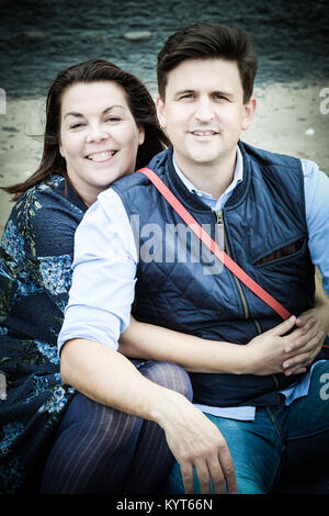 Mann und Frau, Eltern, Paar, umarmen, mit Blick auf die Kamera in [Songbook] Bay, Yorkshire, Großbritannien Stockfoto