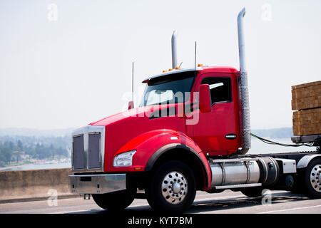 Eine einfache moderne leistungsfähige hell rot Big Rig Semi Truck mit Tag cab für den lokalen Transport von kommerziellen Ladung und hohen Chrom Rohr bestimmt Stockfoto