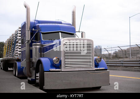 Angesichts der Blue American Classic beliebten kraftvoller Big Rig Semi Truck Traktor mit riesigen kühlergrill und Chrom Zubehör und hohen Auspuffrohr mit flachen Bett Stockfoto