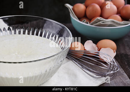 Schale hausgemachter Pfannkuchenteig Mix mit Frische braune Eier im Hintergrund. Extrem geringe Tiefenschärfe. Perfekt für Faschingsdienstag. Stockfoto