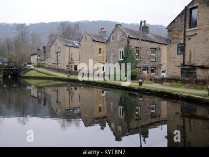 Häuser neben der Rochdale Canal in Hebden Bridge mit Reflexionen im Wasser und Schleusentore in der Ferne Stockfoto