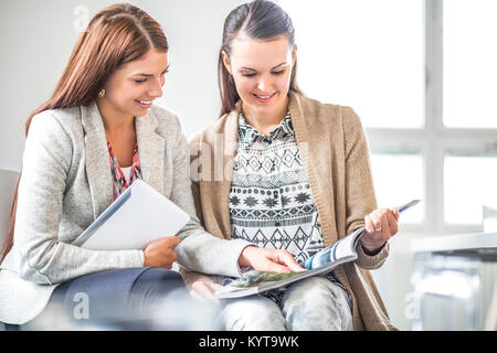 Junge Geschäftsfrau etwas im Buch zeigt den weiblichen Kollege im Büro Stockfoto