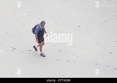 Ansicht eines mittleren Alter kaukasischer Mann gehen über einen Sandstrand im Sommer, Großbritannien Stockfoto