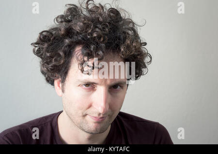 Portrait einer jungen, kaukasische Brunet, lockigen blonden Mann in die Kamera schaut auf einem weißen Hintergrund. Stockfoto