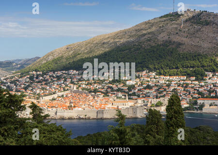 Gebäude auf dem Hügel und Berg Srd in Dubrovnik, Kroatien, gesehen von der grünen Insel Lokrum an einem sonnigen Tag. Stockfoto