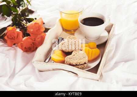 Frühstück und rote Rosen im Bett für den Valentinstag Stockfoto