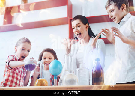 Gemeinsam Spaß haben. Sehr emotional Gruppe von Schülern vor, die neben ihrer Lehrerin für Chemie und praktischer Experimente in der Schule Laboratorien Stockfoto