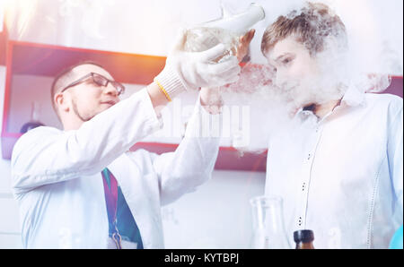 Ein wenig Rauch. Neugierige Schüler und ein männlicher Chemie Lehrer führen ein Experiment in der Schule Labor und Spaß mit einem Abzug Appe Stockfoto