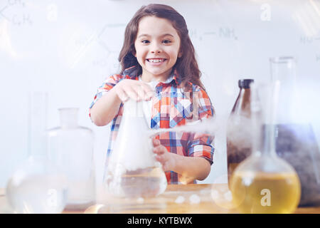 So aufgeregt, neue Dinge zu lernen. Elementare Studentin grinste breit, die während der Arbeit mit einer Chemie und führen ein Experiment während einer Ch Stockfoto