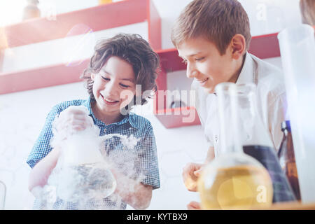 Zukünftige Wissenschaftler. Happy Boys stehen im Labor und in der Holding ein dampfender Isolierflasche während auf einer Schule Projekt während eines Chemie Lektion arbeiten Stockfoto