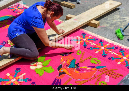 Antigua, Guatemala - April 2, 2015: Frau schmückt Sägemehl Heilige Woche Prozession Teppich in der Stadt mit den berühmten Heiligen Woche feiern gefärbt Stockfoto