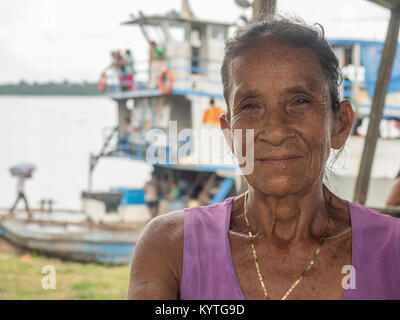 Caballococha, Peru - Dec 11, 2017: Porträt einer Frau, die mit einem roten Haut auf dem Hintergrund der Frachtboot in den Amazonas Dschungel Stockfoto