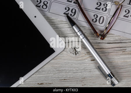 Digitale Tablet auf einem Holztisch mit einer Brille, Kalender und Kugelschreiber Stockfoto